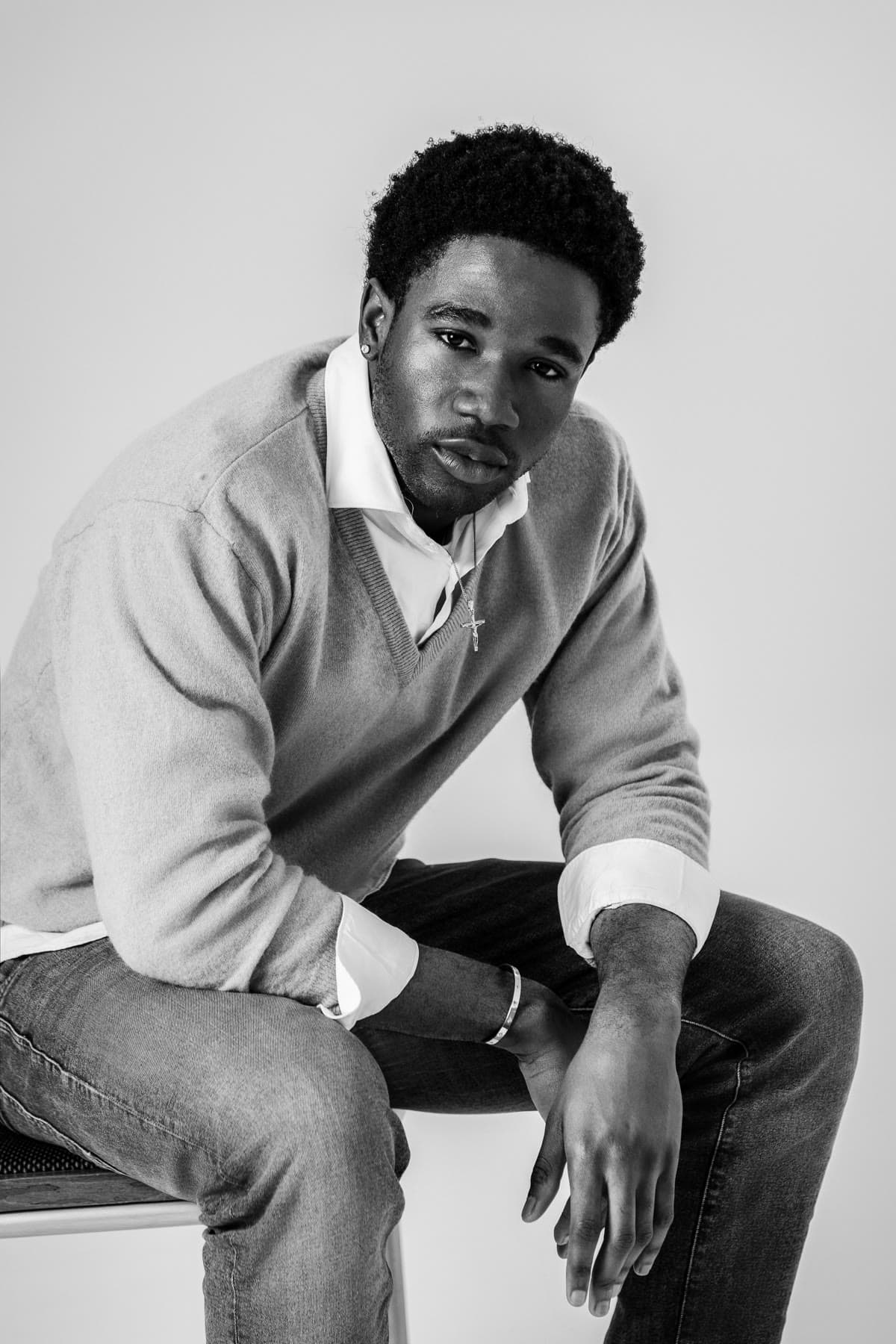 Seated menswear portrait in a V-neck knit and open collar, black and white